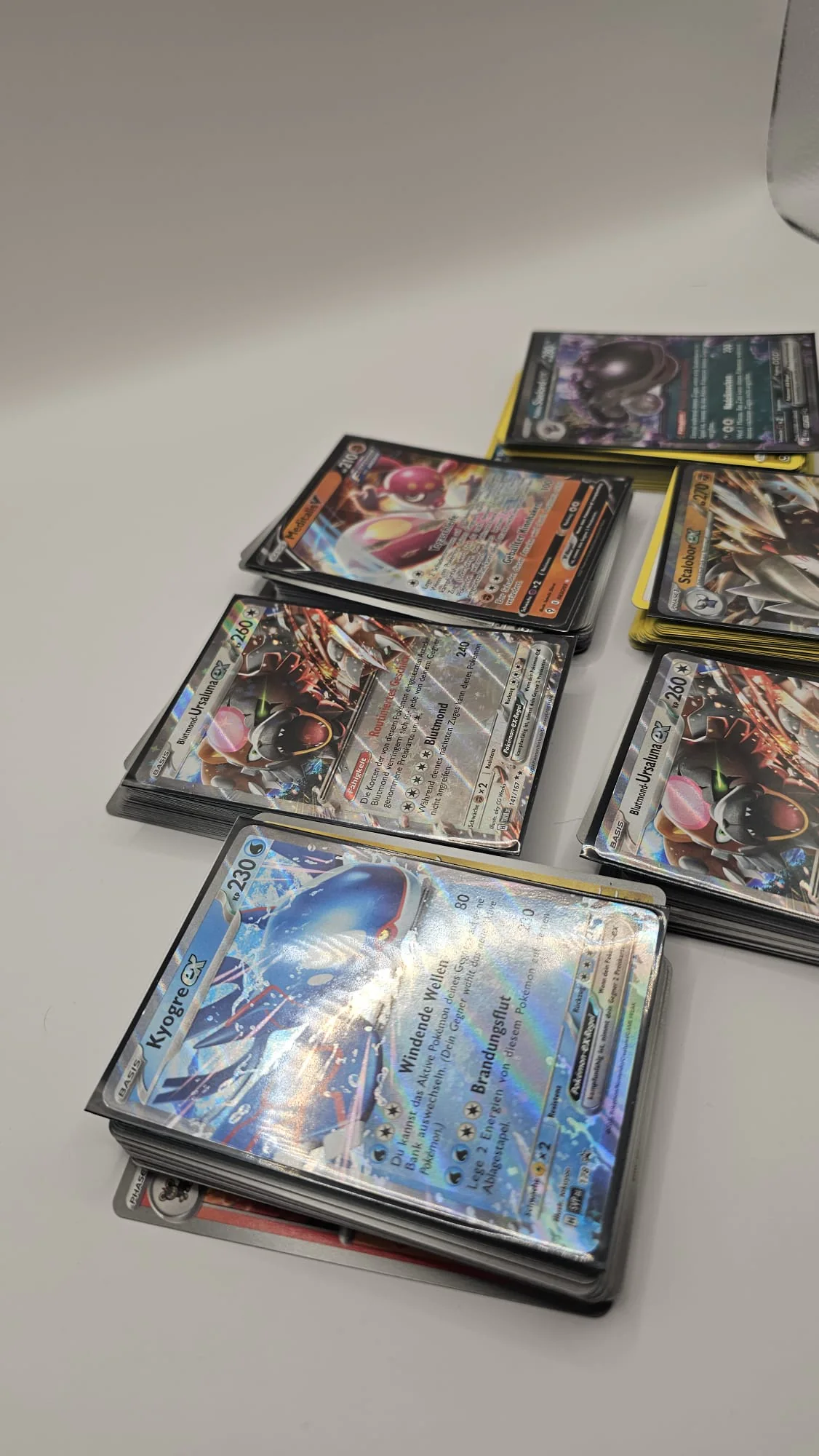 Pokémon-Karten unter starkem Licht mit deutlich sichtbaren Reflexionen auf der holografischen Oberfläche