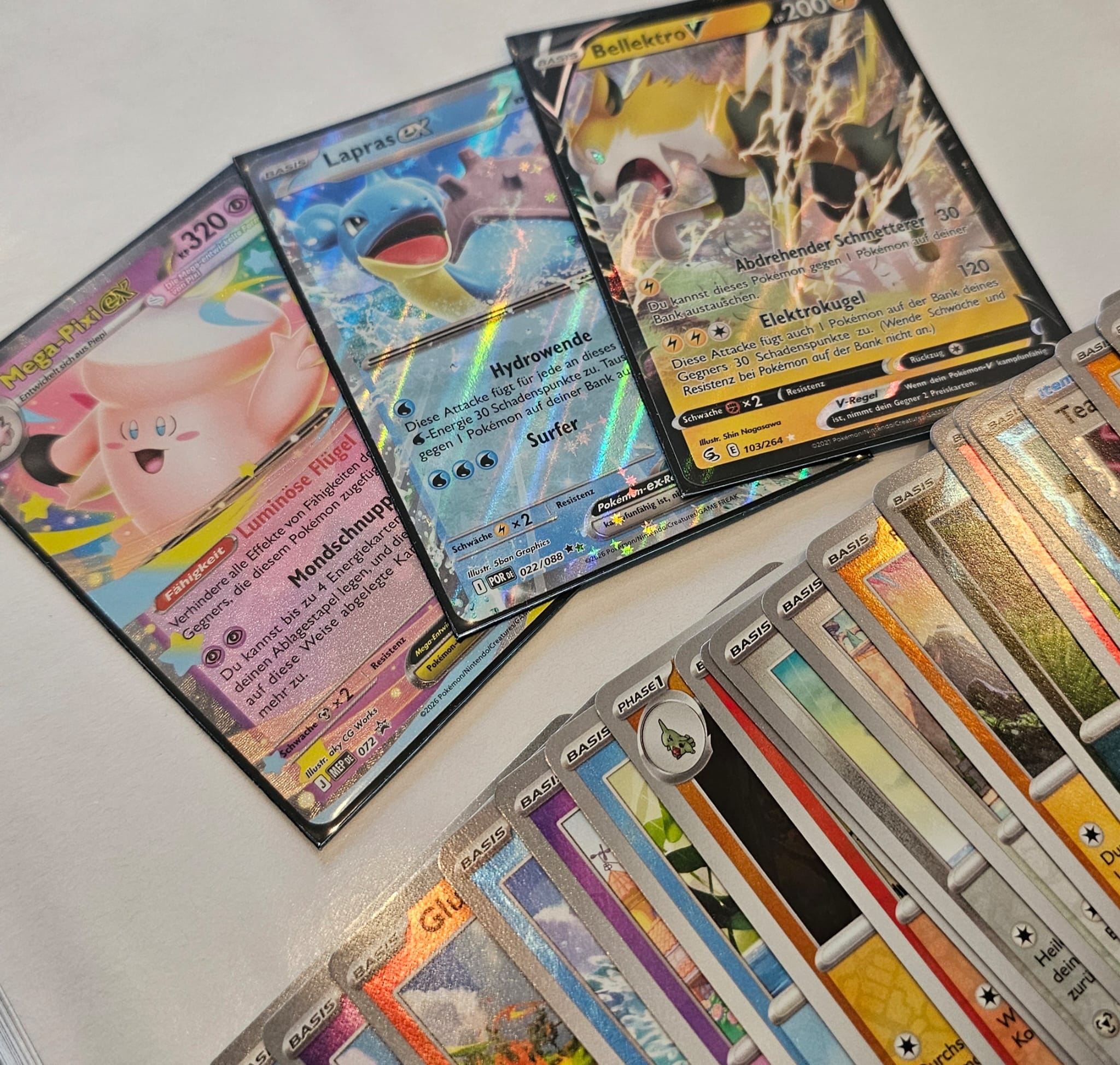Besondere Pokémon-Einzelkarten neben einem Stapel aus normalen und holografischen Karten