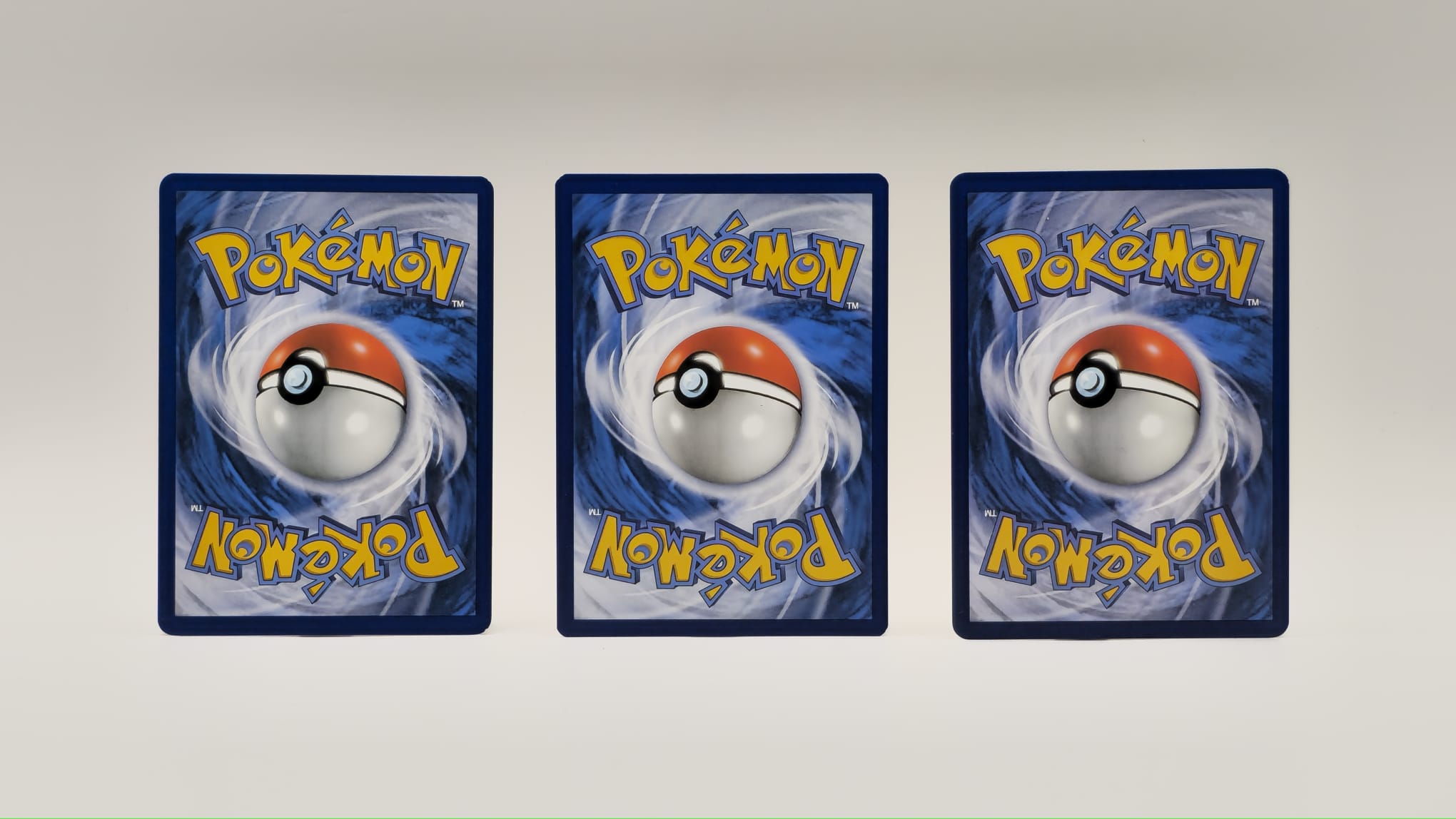 Rückseiten von drei Pokémon-Karten mit unterschiedlich stark sichtbaren Gebrauchsspuren